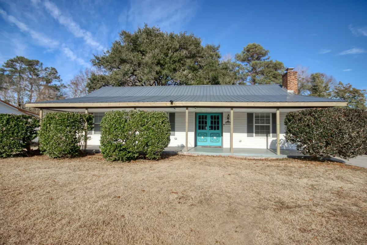 This exterior shot captures the welcoming front door, landscaped bushes, and the roofline with a visible chimney. The scene feels lively and friendly, with space for outdoor activities like children playing or hosting gatherings in the yard.